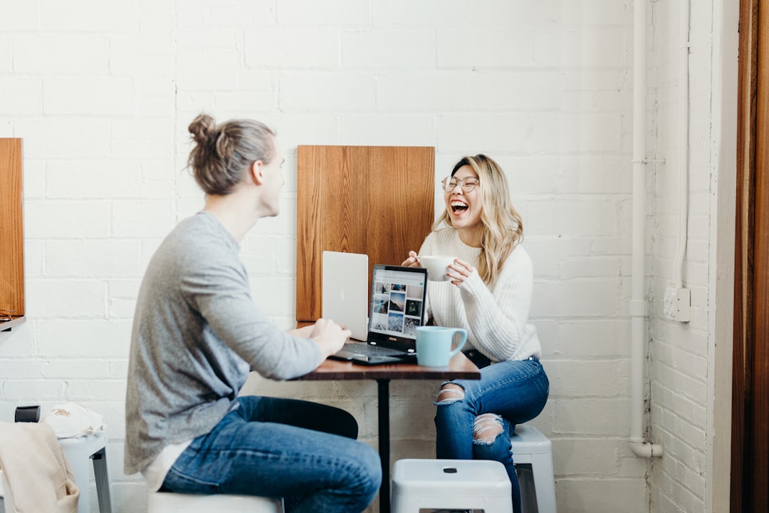 BusinessMeeting Two people chatting and laughing at a table with their laptops open